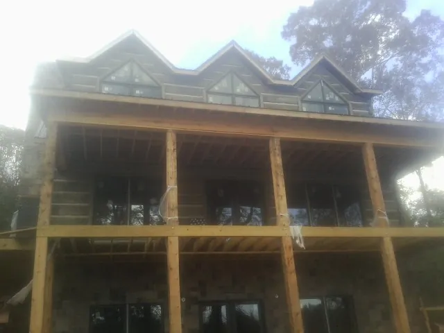 Dormers and porch framing on a large log home under construction — Roof Coating work by our crew in Solen