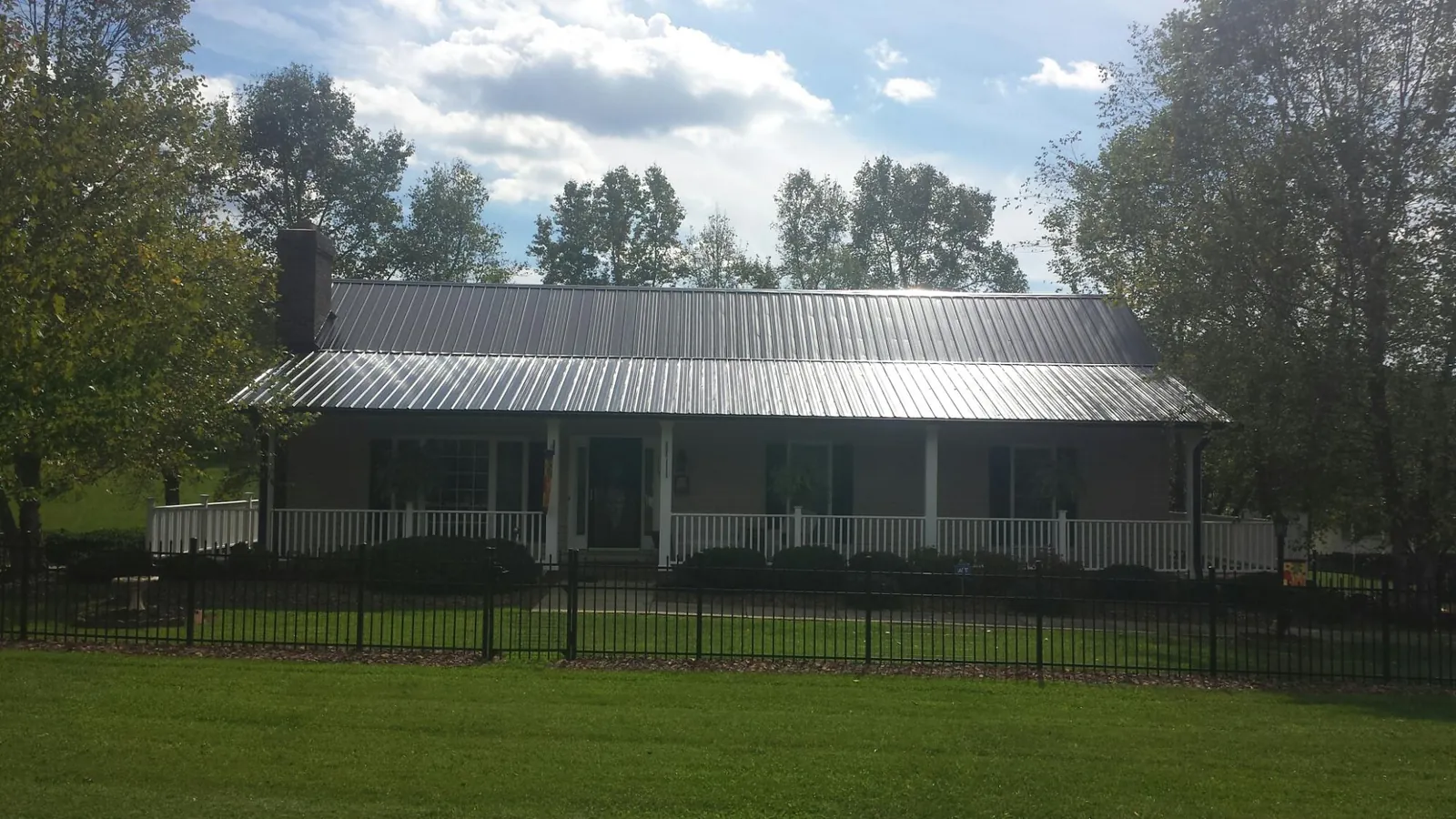 Gray metal roof on a brick ranch with a full width front porch — Gutter Guard Installation work by our crew in Solen