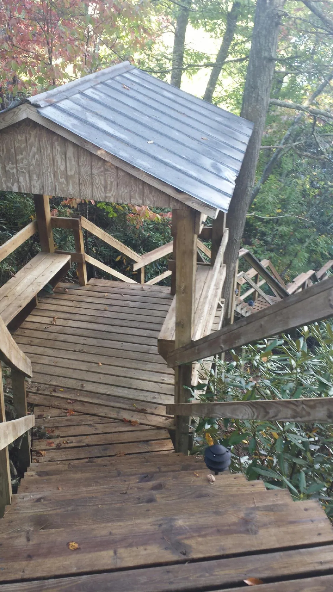 Metal roofed shelter over wooden steps on a wooded walkway — Skylight Repair & Installation work by our crew in Solen