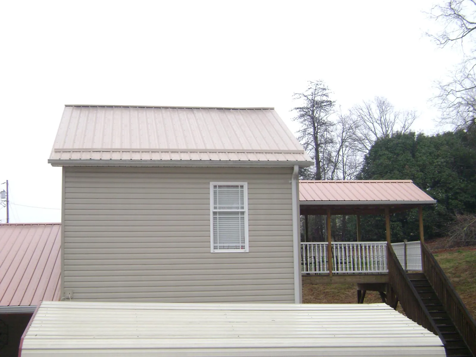 Tan metal roofs on a two story addition and attached porch, from a Roof Replacement job in Solen