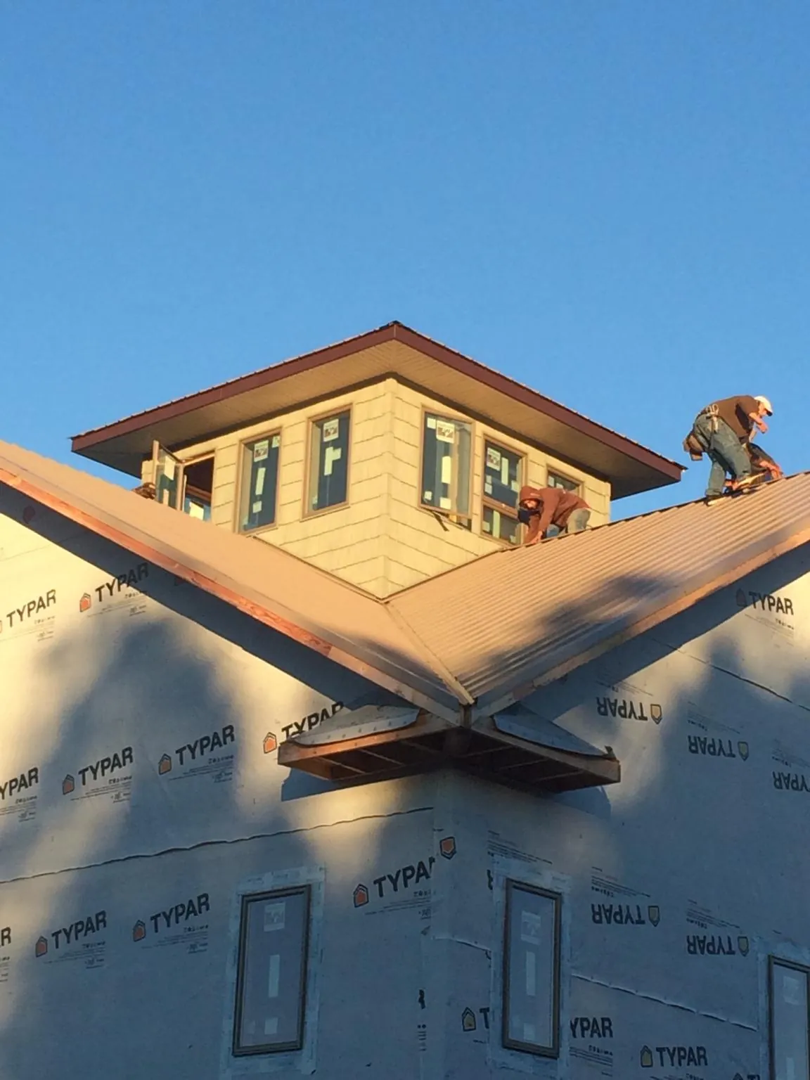 Roofers working around a rooftop cupola on a new metal roof at sunset — Roof Waterproofing in Solen by Roofing Brothers